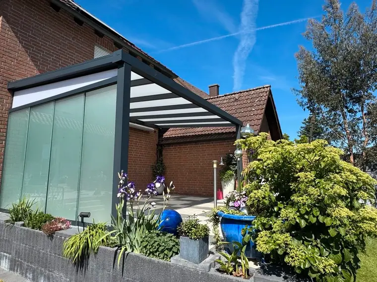 Terrassenüberdachung mit Glas-Schiebewand als Windschutz zum Garten
