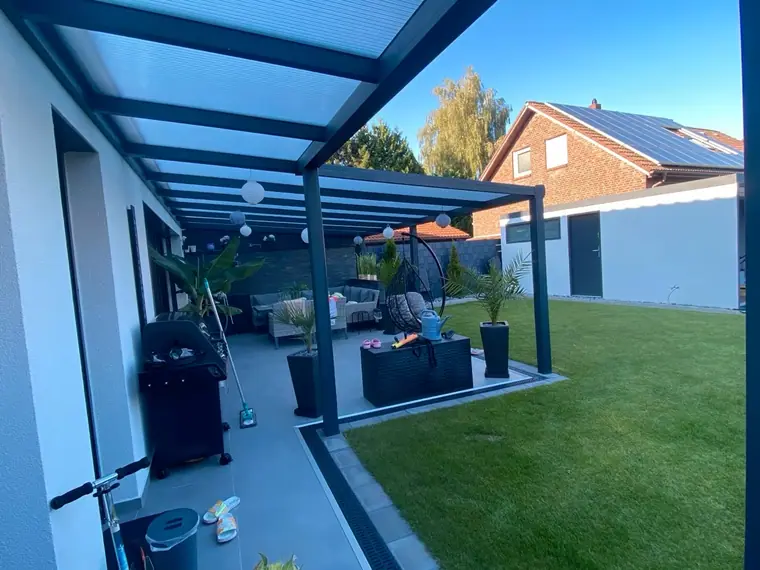 Terrassenüberdachung an einem weissen Haus, Blick entlang der Terrasse bei blauem Himmel