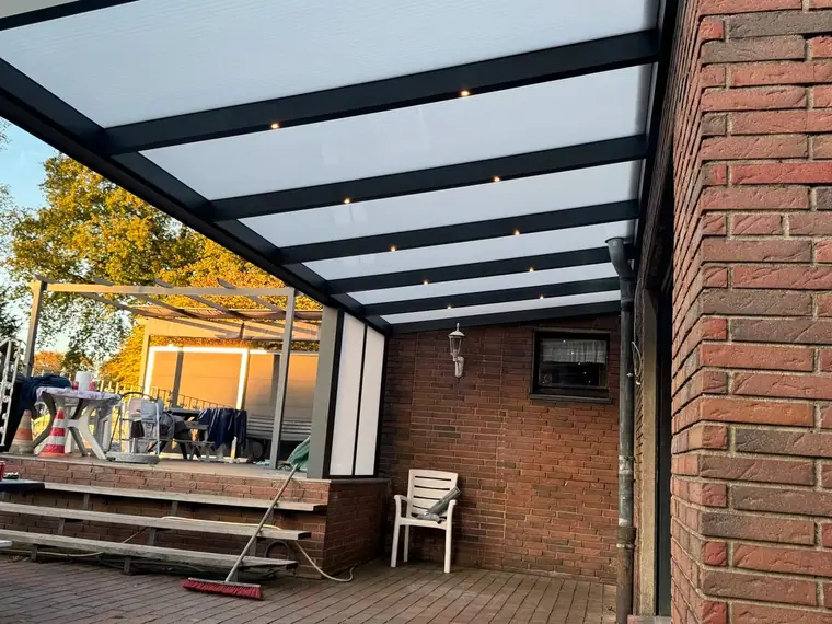 Terrassenüberdachung an Klinkerfassade mit eingebauten LED-Spots im Dachprofil