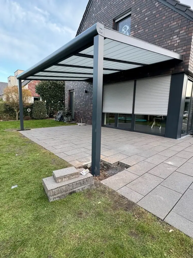 Terrassenüberdachung über einer Terrasse mit Schiebetür und Rollladen