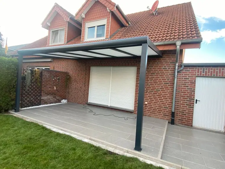 Terrassenüberdachung an einem roten Klinkerhaus mit gefliester Terrasse