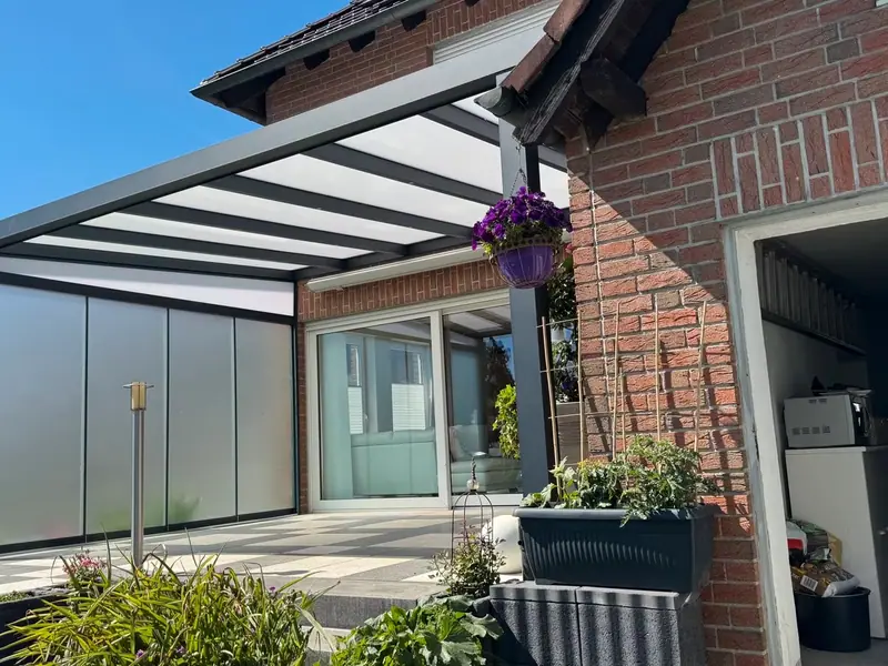 Glas-Schiebewand als Windschutz unter einer Terrassenüberdachung
